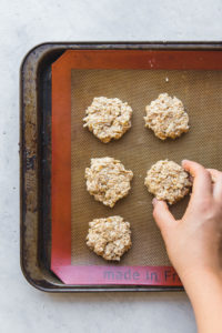 placing banana oatmeal breakfast cookies onto baking tray lined with silicone mat