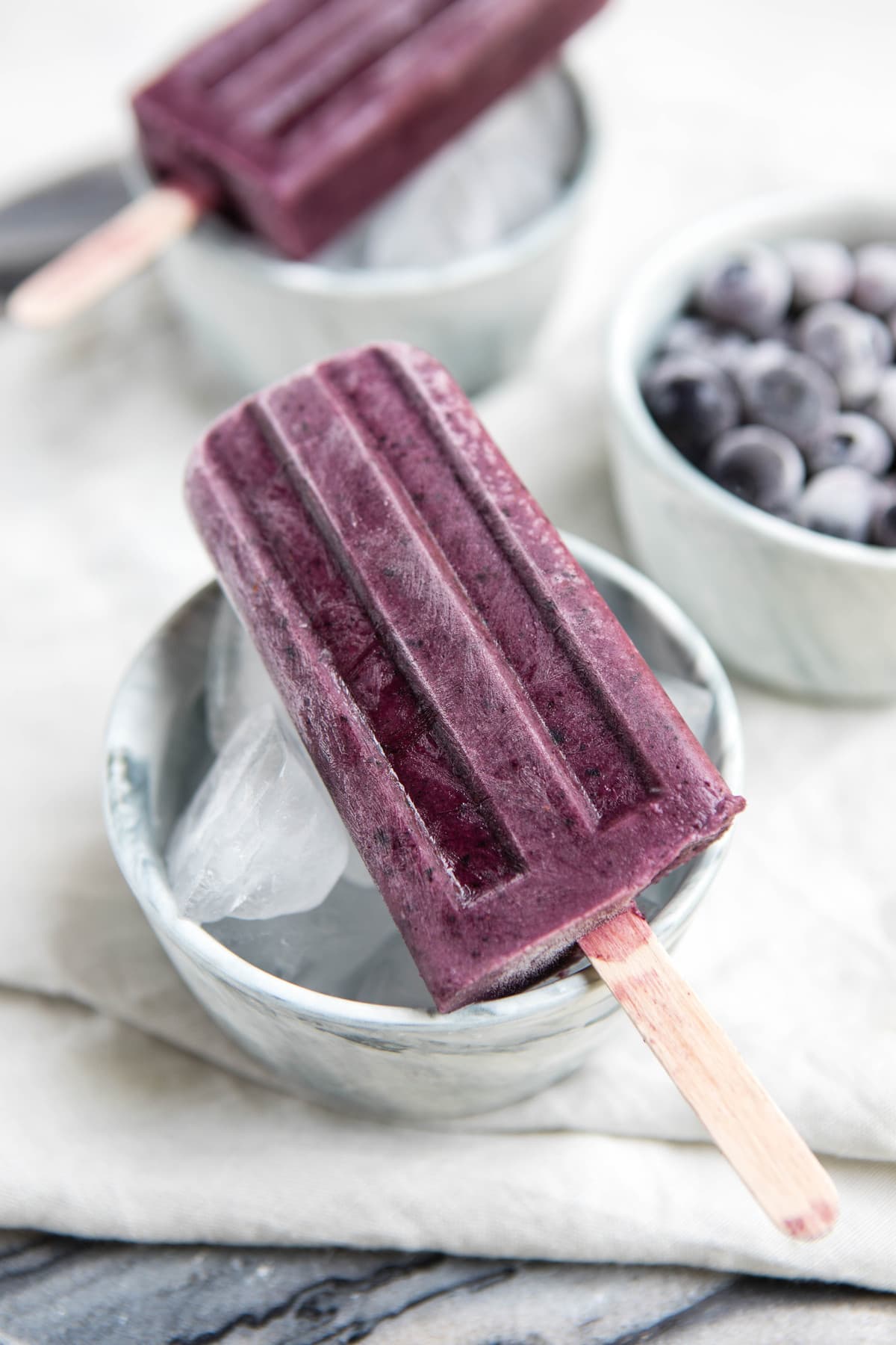 blueberry maqui popsicle in white bowl on marble background