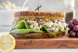 chickpea salad sandwich with lettuce and grapes on wood serving platter
