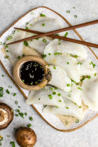 overhead shot of mushroom dumplings with green onions and sesame seeds