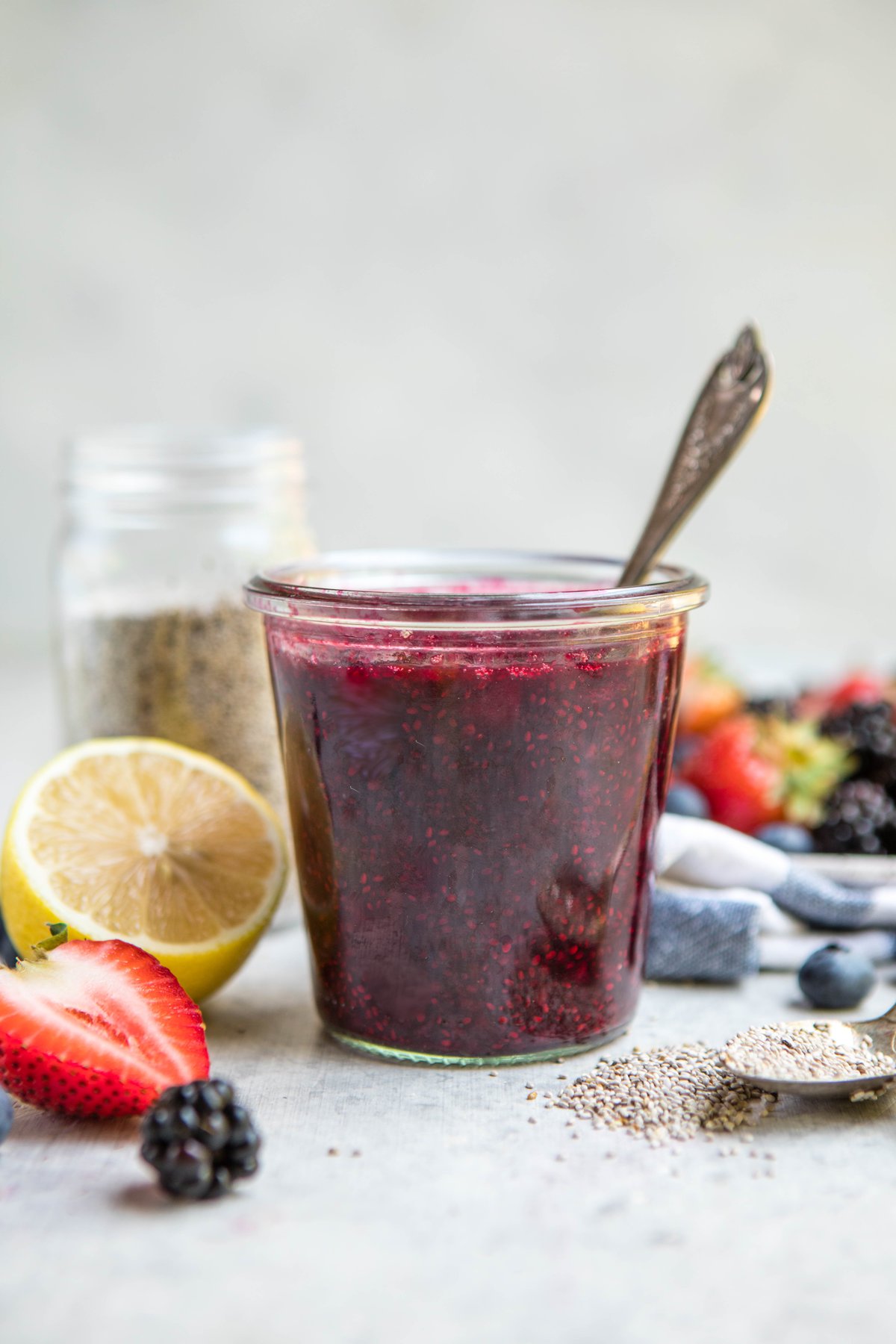glass jar of chia seed jam surrounded by fresh berries