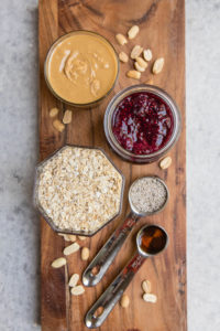 ingredients for pbj overnight oats on wooden cutting board