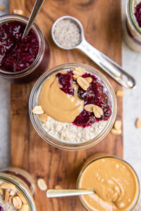 overhead shot of jar of pbj overnight oats with jars of chia jam and peanut butter