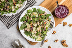 quinoa & arugula salad on white plate and wood cutting board
