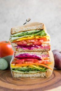 rainbow veggie sandwiches cut in half and wrapped in parchment paper