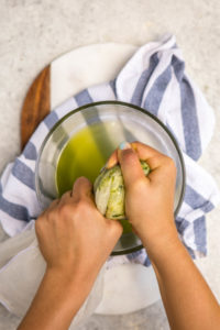 hands squeezing zucchini using nut milk bag