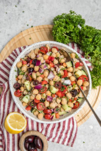 large bowl of chickpea salad on wood cutting board