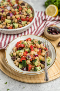 shot of chickpea salad in white bowl on wood cutting board