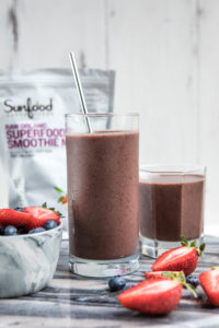 prepares smoothies in glass jars with bag of sunnfood's superfood smoothie mix