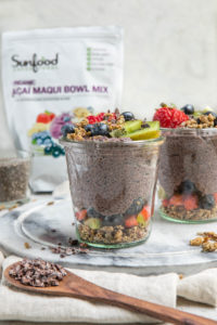 glass jars of acai chia pudding with sunfood acai maqui bowl mix in the background