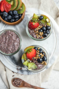 glass jars of acai chia pudding topped with various toppings