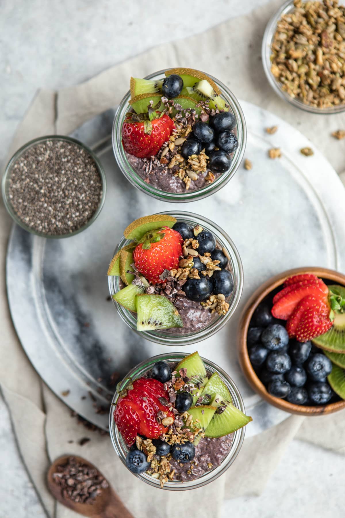 overhead shot of acai chia pudding jars topped with fresh fruit and granola