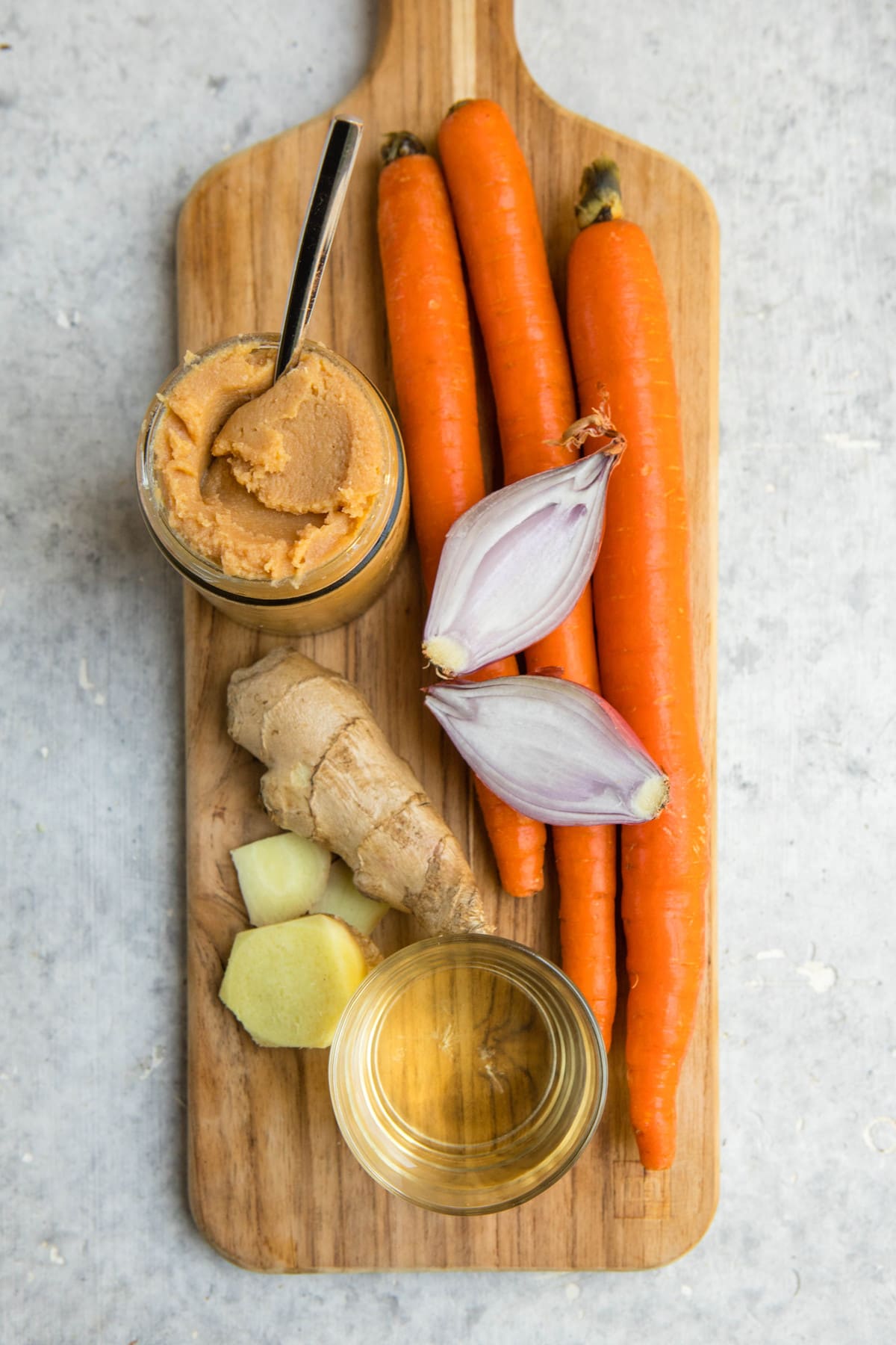 ingredients for carrot ginger dressing on wood cutting board