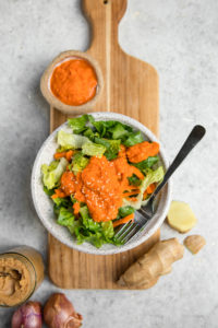 carrot ginger dressing with ingredients on wood cutting board