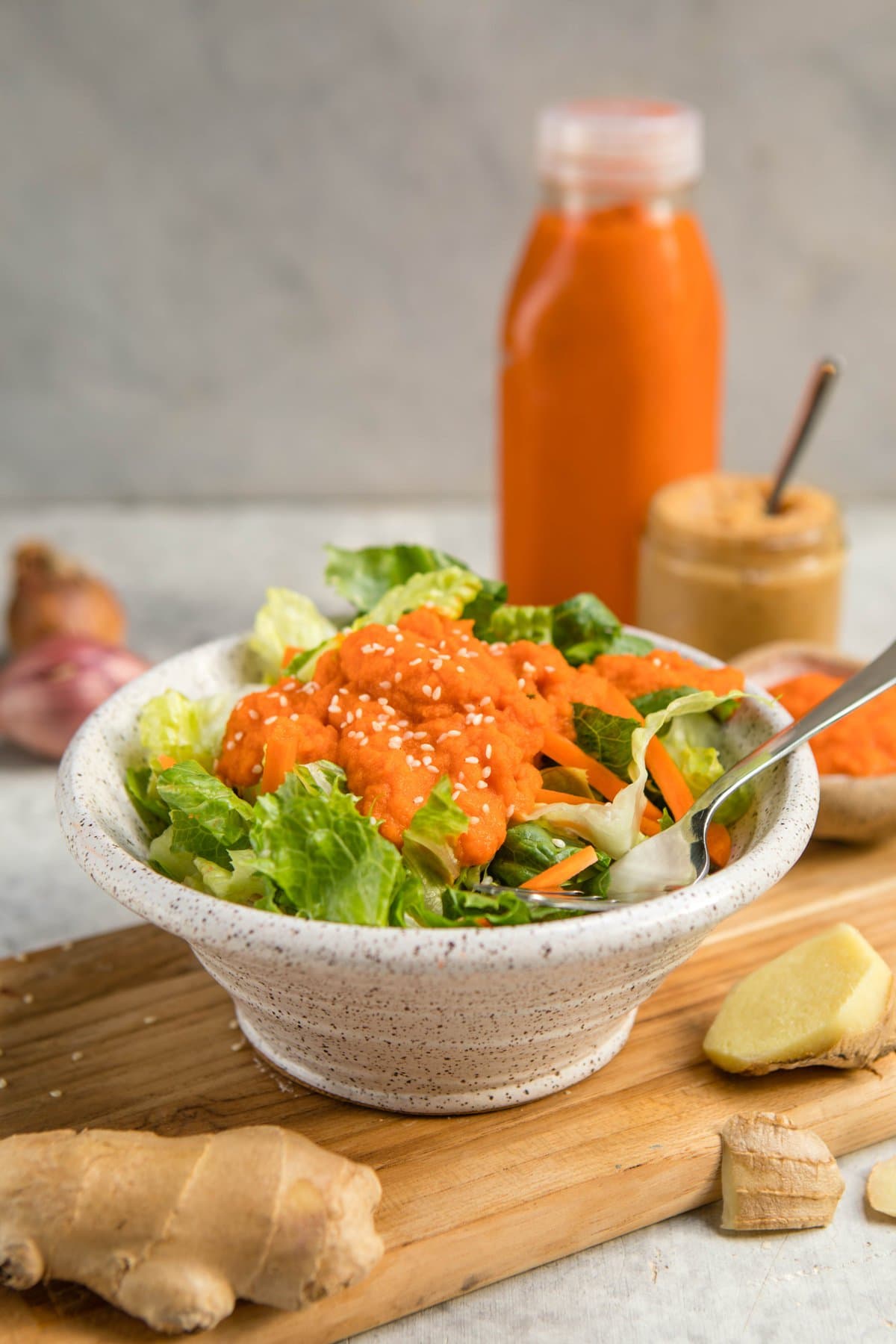 white bowl of lettuce and carrots topped with carrot ginger dressing