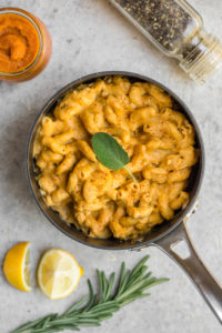 cooked pumpkin pasta in black pot on grey background