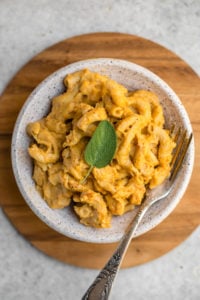 close up photo of pumpkin pasta in white bowl with fork
