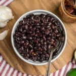 bowl of cooked black beans on wood cutting board