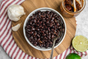 bowl of cooked black beans on wood cutting board
