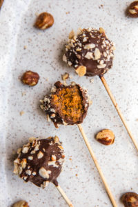 pumpkin spice cake pops on white serving tray with pieces of hazelnuts