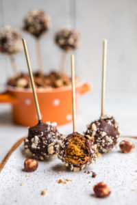 pumpkin spice cake pops on white serving tray with bite taken out of one cake pop