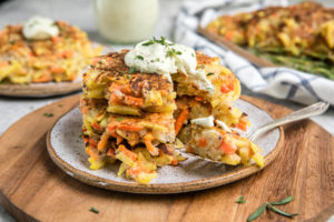 stack of root vegetable pancakes with cashew cream on wood cutting board