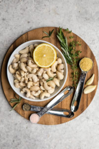 ingredients for rosemary garlic cashew cream on round wood cutting board