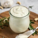 rosemary garlic cashew cream in glass jar with fancy knife on wood cutting board