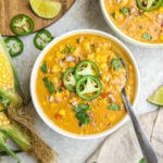 bowl of corn chowder topped with jalapenos on grey stone background