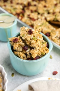 small teal bowl filled with clusters of tahini cardamom granola