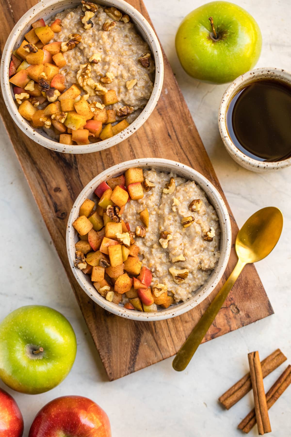 two bowls of cinnamon apple oatmeal topped with cinnamon apples and walnuts
