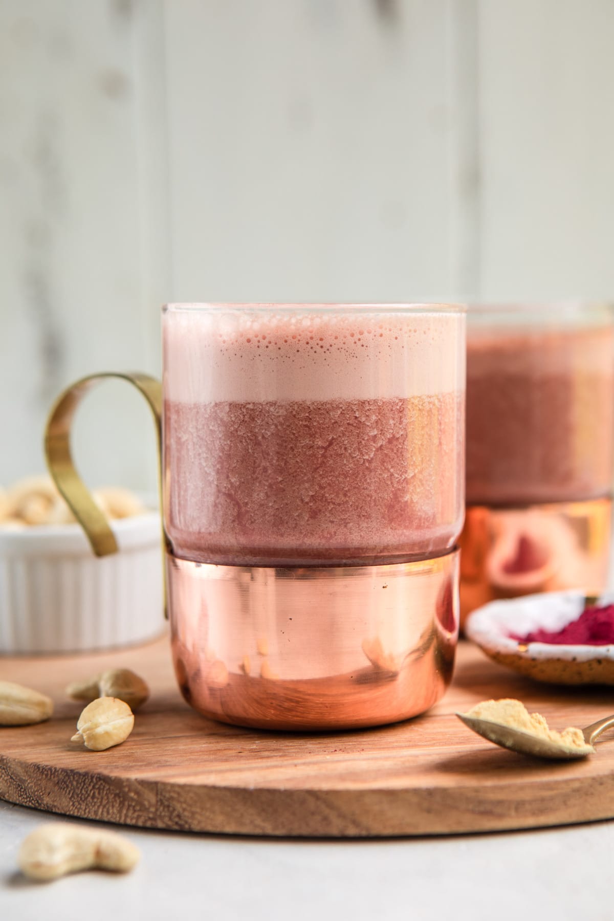 frothy pink beet latte in clear glass mug with gold handle 