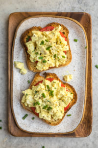 vegan egg salad on two pieces of toast with fresh chives and black pepper