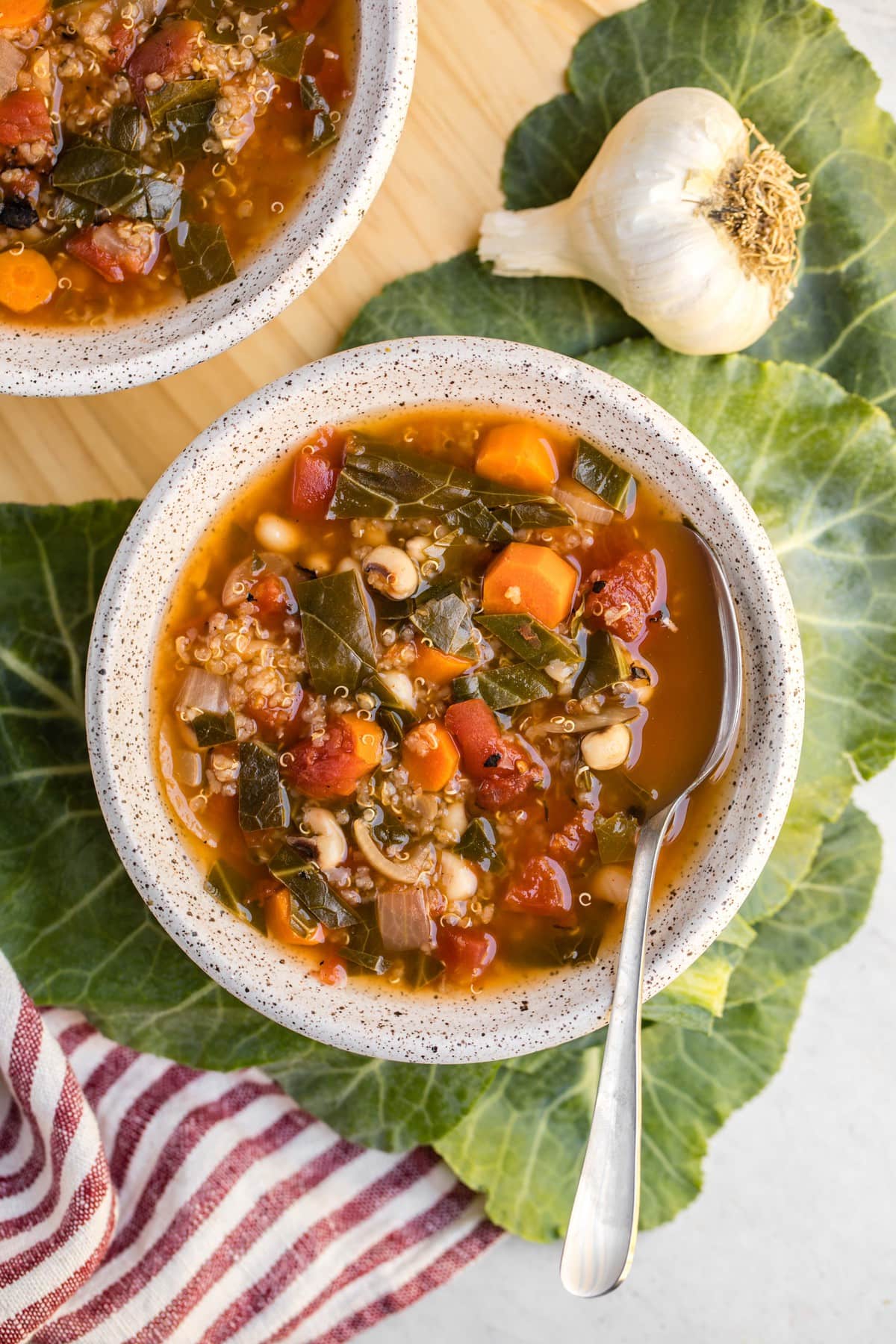 bowl of black-eyed pea soup with quinoa on collard greens and with silver spoon