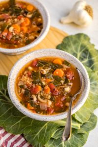 angled view of bowl of black-eyed pea soup with quinoa on top of collard greens