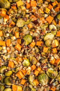 close up photo of roasted vegetable casserole topped with pecans