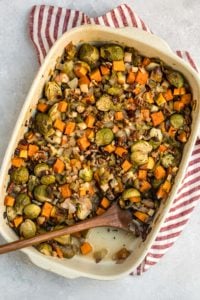 white casserole dish filled with roasted vegetable casserole and wooden spoon