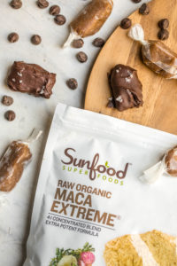 healthy salted caramel bites on round wood cutting board with bag of sunfood maca extreme powder