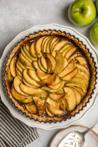 close up shot of cooked salted caramel apple tart with silver pie serving spoon