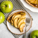 slice of salted caramel apple tart on small white plate with black striped napkin