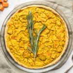 sweet potato & rosemary quiche in glass pie tin topped with fresh rosemary on grey backdrop