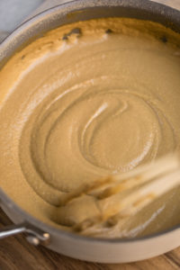 grey saucepan with whisk and thickening tahini gravy