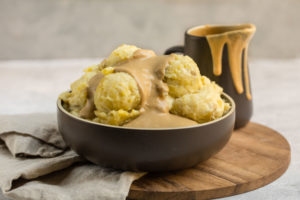 brown bowl filled with mashed potatoes and topped with tahini gravy