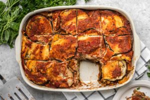 large white casserole dish of baked eggplant lasagna with one slice taken out