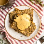 two slices of lentil load on small white plate topped with tahini gravy