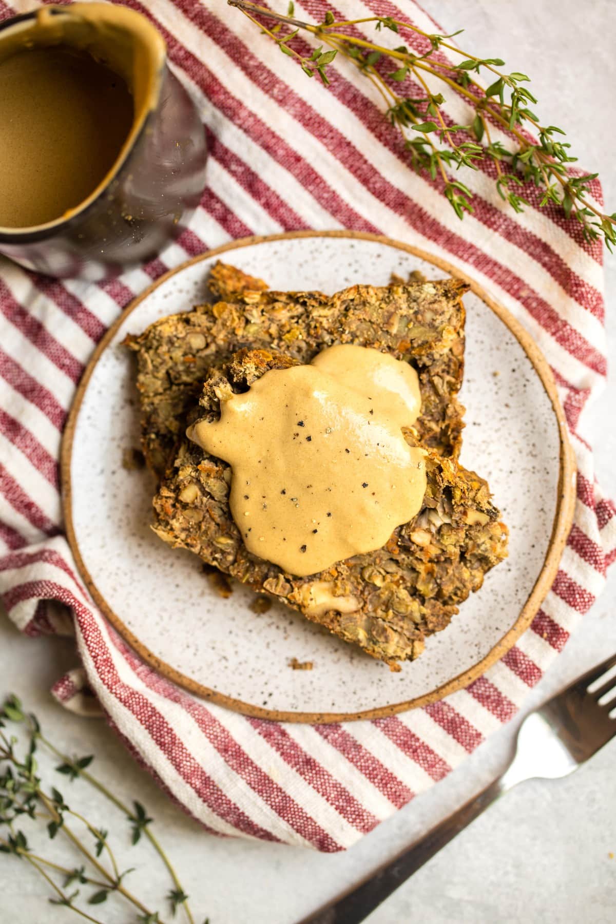 two slices of lentil load on small white plate topped with tahini gravy