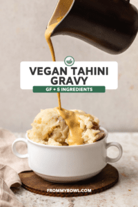 Hand pouring tahini gravy over pile of mashed potatoes in white bowl
