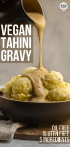 gravy being poured over mashed potatoes in black bowl