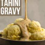 gravy being poured over mashed potatoes in black bowl