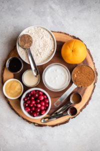 ingredients for cranberry orange bread on round wood cuttinng board